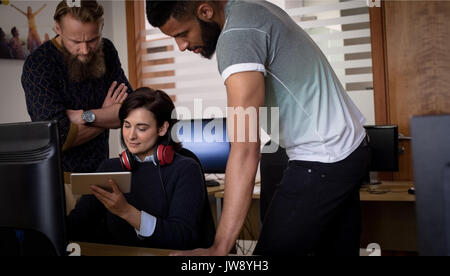 Collègues using digital tablet while working at desk in office Banque D'Images