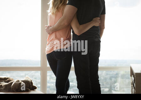 Vue arrière du couple hugging les uns les autres dans la salle de séjour à la maison Banque D'Images