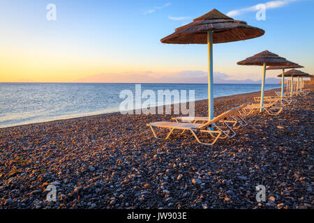 Parasols et transats sur la plage de galets. Banque D'Images