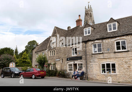 Femmes assises à l'extérieur du café et produits laitiers sur Market Street dans la ville de Cotswold Minchinhampton UK Banque D'Images