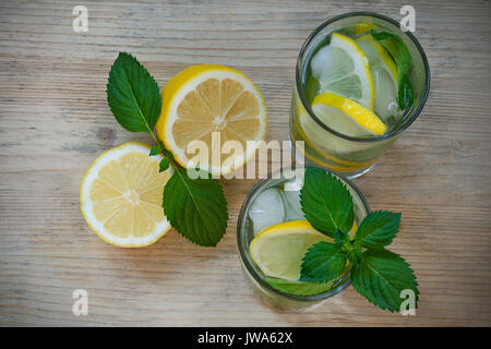 Boisson rafraîchissante avec de l'eau, citron, menthe, glace dans les verres sur un fond de bois. L'eau detox maison Banque D'Images