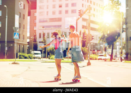 Teenage couple riding skateboards on city street Banque D'Images