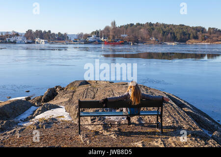 Jeune femme est reposant sur un banc sur la côte rocheuse. Petite île norvégienne du fjord d'Oslo Banque D'Images