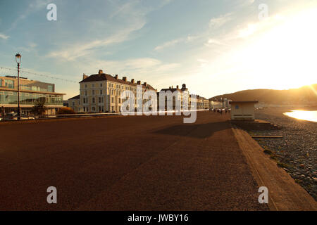 Les gens qui marchent le long de la promenade de Llandudno en fin de soirée avec le soleil en arrière-plan de Great Orme. Photographie prise le 16 juillet 2017. Banque D'Images