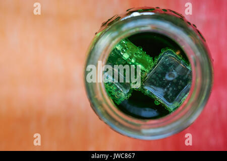 Bouteille de l'eau aérée par le haut. avec des cubes de glace de couleur verte Banque D'Images