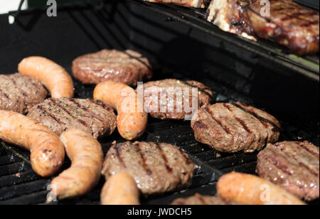 Des hamburgers, des steaks et des saucisses grillées sur un barbecue extérieure Banque D'Images