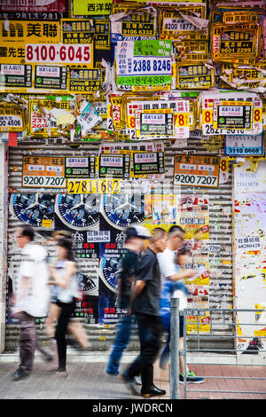 HONG KONG - Juillet 10, 2017 : affiches, dépliants et publicités remplir chaque pouce d'un mur dans le quartier du centre-ville animé de Mong Kok hurri comme piétons Banque D'Images