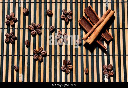 Des grains de café frais sont disposés sur la surface en bois avec de magnifiques et beaux modèles. Près de la cannelle est mis à baguettes. Les produits sont fr Banque D'Images