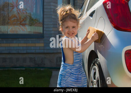 Petite fille mignonne lave voiture en journée ensoleillée Banque D'Images