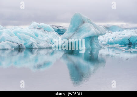 Les icebergs bleu flottant sur l'eau calme avec des réflexions Jokulsarlon glacier lagon. L'Islande. Banque D'Images