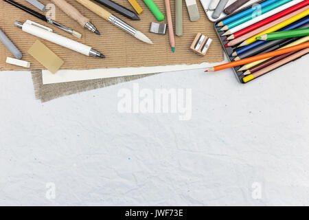 Outils de dessin de l'artiste : divers Crayons, craies de couleur, pinceaux sur fond de papier recyclé Banque D'Images