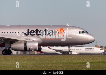 Jetstar Airways avion Airbus A320 à l'atterrissage à l'aéroport de Sydney avec un avion de Qantas en arrière-plan. Banque D'Images