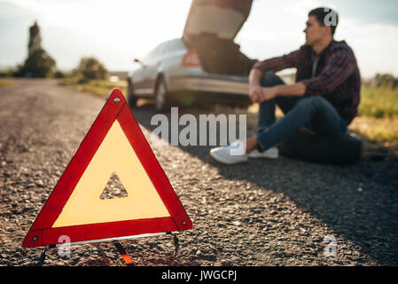 Concept de voiture cassé, panne triangle sur route asphaltée. Problème avec véhicule, panneau d'avertissement Banque D'Images