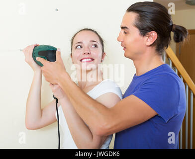 Heureux homme et femme mur de forage avec la perceuse à la maison Banque D'Images