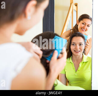 Young smiling girl doing hairstyle pour son amie Banque D'Images