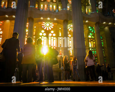 La lumière du soleil du soir est entrant via le Windows de l'peint façade occidentale de la cathédrale de la Sagrada Familia de Barcelone qui est bondée de touristes Banque D'Images