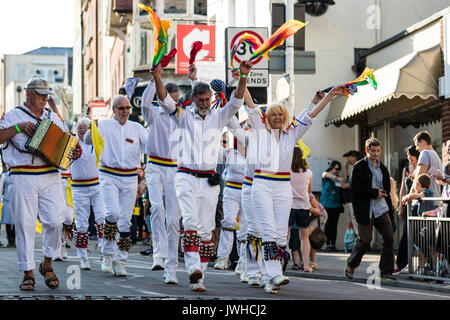 Folk Festival annuel de Broadstairs Semaine parade. Côté Morris Dancers marchant le long de high street, agitant des mouchoirs multi-couleurs dans l'air au-dessus de leurs têtes. Banque D'Images