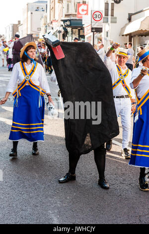 Au cours de la parade annuelle de Broadstairs festival de la semaine folklorique. Un homme emblématique Ossie, habillé en oiseau noir, regarde spectateur avec danseurs, Morris, autour de lui. Banque D'Images