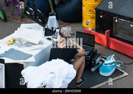 Moscou, Russie, le samedi 12 août 2017. Jour deux visages et dentelles street fashion, sport, festival d'art détient dans Gorky Park les 12 et 13 août. La devise de l'événement est le localisme Sous-culturelle ou soutenir votre scène locale. Sneakerness, street wear, fashion des jeunes de tous les genre, sport de rue, de danse et d'art souterrain - toutes les activités sont les bienvenus. C'est un festival de la jeunesse. Le Parc Gorky est bondé avec des jeunes, beaucoup d'endroits pour montrer votre talent et partager vos compétences. Méconnaissable jeune femme t-shirts bouilloire et le vendeur. Crédit : Alex's Pictures/Alamy Live News Banque D'Images