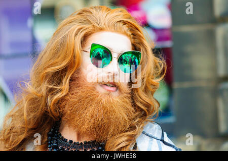Edinburgh, Ecosse, Royaume-Uni. 12 août, 2017. 7ft de haut Gingzilla avec du gingembre artiste faites glisser les cheveux et barbe et portant des lunettes de soleil miroir vert effectue dans les rues de la ville à la fin de la première semaine de la 70e anniversaire de l'Edinburgh International Fringe Festival. Credit : Skully/Alamy Live News Banque D'Images