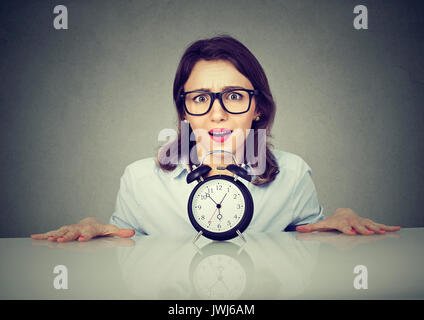 Impatient Woman picking de sous la table avec réveil. La pression du temps concept Banque D'Images