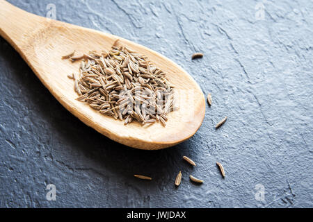 Les graines de cumin à la cuillère sur le fond de la pierre noire, Close up Banque D'Images