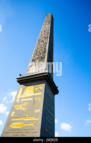 Vue à angle bas de l'obélisque de Louxor sur la place de la Concorde à Paris, avec hiéroglyphes et diagrammes dorés sur le piédestal, contre le ciel bleu. Banque D'Images