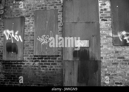 Bâtiment abandonné, abandonné, déserté, scellé, fenêtres en métal boarqué, zone urbaine de délabrage, extérieur en brique dans les ruines emplacement inoccupé Graffiti Banque D'Images