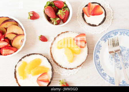 Tarte au chocolat, tartalette avec chocolat blanc et crème de mascarpone, fraises fraîches et orange sur le dessus. Fond de bois gris. Vue d'en haut Banque D'Images