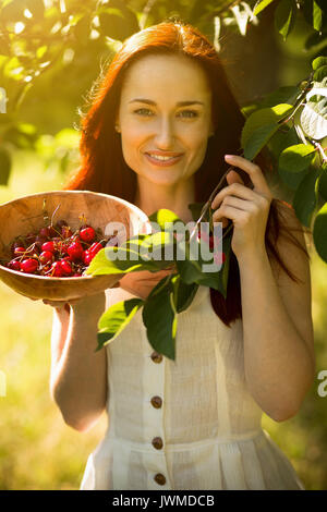 Vue de face de la cueillette des cerises femme foxy attrayant d'arbre. Banque D'Images
