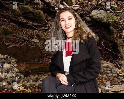 Portrait of a pretty smiling teenage girl in pull et manteau noir dans la nature Banque D'Images