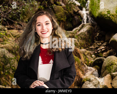 Portrait of a pretty smiling teenage girl in pull et manteau noir dans la nature Banque D'Images