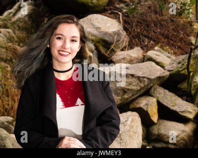 Portrait of a pretty smiling teenage girl in pull et manteau noir dans la nature Banque D'Images