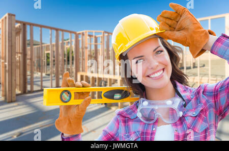 Niveau Female Construction Worker Holding portant des gants, casque et lunettes de protection au chantier de construction. Banque D'Images