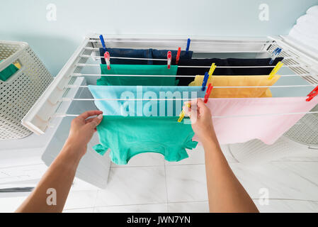 High Angle View of Woman Hanging chiffon propre humide sur corde à linge avec des vêtements Peg Banque D'Images