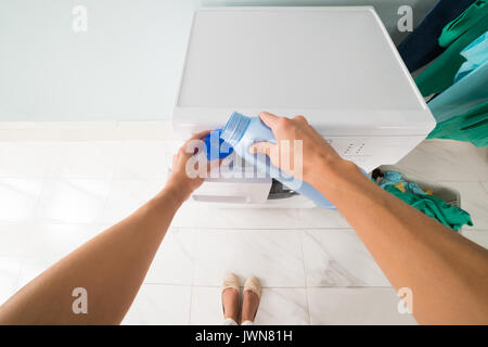 Perspective de POV de Woman Pouring détergent dans un couvercle près de lave-linge dans buanderie Banque D'Images