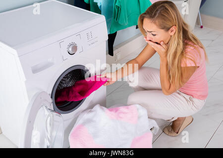Choqué Angry Woman Looking at tachée chiffon blanchie dans un lave-linge à la Buanderie Banque D'Images