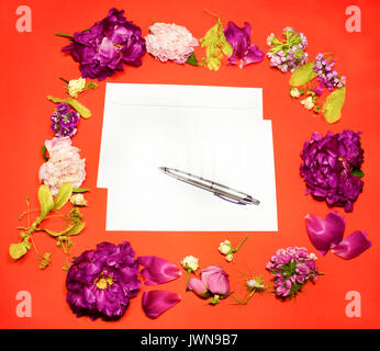 Fleurs, enveloppe et un stylo sur un fond rouge Banque D'Images
