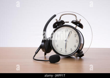 Au cours d'une spirale casque retro réveil avec sonnerie sur une table en bois ou un bureau dans une image conceptuelle with copy space Banque D'Images