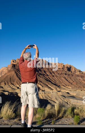 Homme âgé de 60 à 70 ans prenant des photos avec un téléphone portable à Castle Valley, Utah, États-Unis Banque D'Images