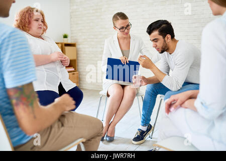 Portrait de jeune homme qui crie dans cercle de soutien de la thérapie de groupe séance de problèmes de partage avec femme psychiatre Banque D'Images