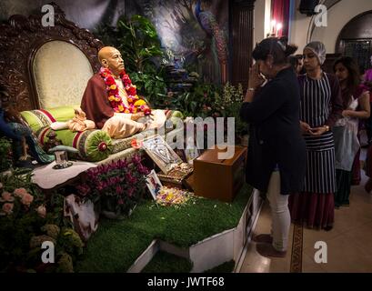 Une femme paie ses égards en face d'une représentation d'Abhay Charanaravinda Bhaktivedanta Swami Prabhupada, fondateur de le mouvement Hare Krishna, au cours de la fête hindoue Janmashtami au Manoir Bhaktivedanta Hare Krishna à Watford. Banque D'Images