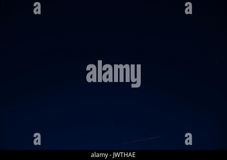 La lumière étincelante qui ressemble à paillettes ou la neige tombe lentement sur un fond bleu. Les rayons de lumière briller faiblement. Banque D'Images