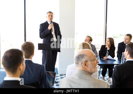 Le président d'affaires avec microphone devant public, conférence, séminaire concept Banque D'Images