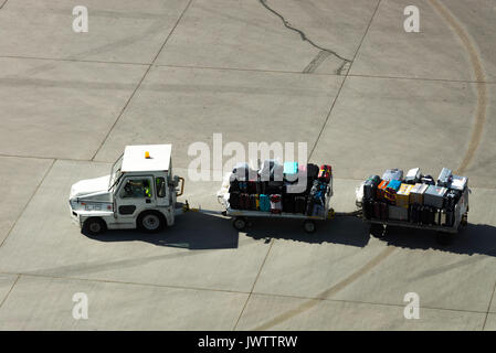 Valises sur chariots tiré par un remorqueur sur la chaussée avant le chargement d'un avion à l'Aéroport International de Calgary Alberta Canada Banque D'Images