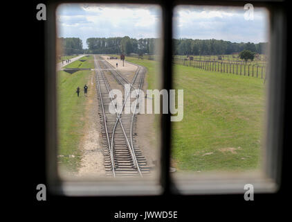 Les visiteurs marchent à travers l'ancien camp de concentration d'Auschwitz-Birkenau à Oswiecim, Pologne, 26 juin 2017, photographiés à travers une fenêtre de la tour de guet. La principale organisation paramilitaire de l'Allemagne nazie, SS (Schutzstaffel, allumé. L'Escadron 'Protection'), a couru le camp de la mort et de concentration entre 1940 et 1945. Les personnes expulsées ont été choisis en différents groupes sur la rampe entre les pistes juste après leur arrivée à Birkenau. Les personnes qui n'ont pas été en mesure de travailler (les personnes âgées, faibles, femmes, enfants) sont parfois envoyés à la chambre à gaz sans enregistrement. Environ 1,1 à Banque D'Images