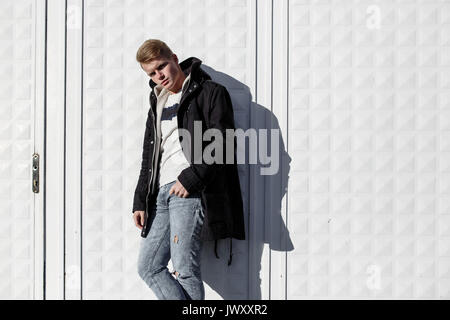 Jeune homme élégant redhead dans le quartier branché d'outfit posing contre l'arrière-plan urbain Banque D'Images