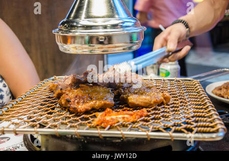 La cuisson de la viande sur un barbecue coréen Koream dans un restaurant. Le repas est préparé sur le grill sur la table devant les invités, Banque D'Images