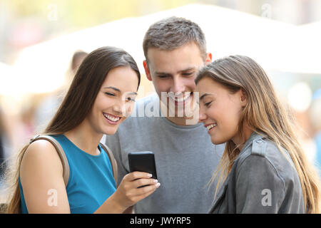 Trois amis heureux smart phone partage du contenu sur la rue Banque D'Images