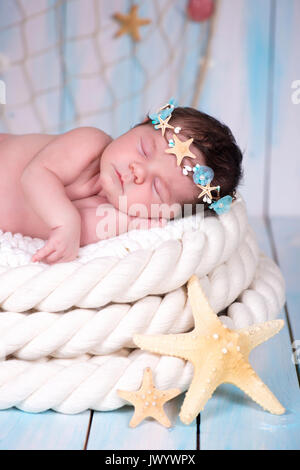 Fermer portrait d'une fille nouveau-né sommeil dans le cerceau maritime d'étoiles de mer et perles Banque D'Images